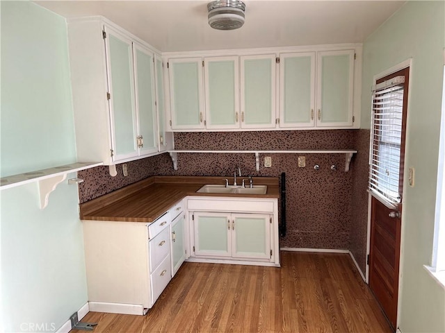 kitchen with a wealth of natural light, sink, white cabinetry, and light hardwood / wood-style floors