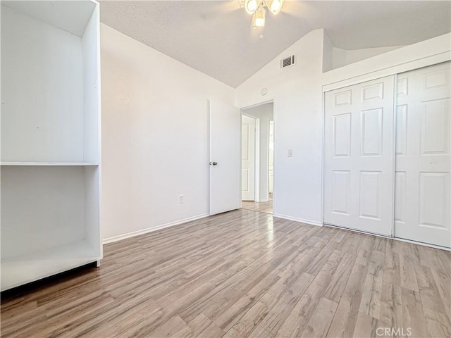 unfurnished bedroom featuring lofted ceiling, light hardwood / wood-style flooring, and a closet