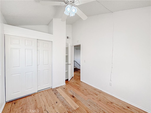 unfurnished bedroom featuring high vaulted ceiling, light wood-type flooring, ceiling fan, and a closet