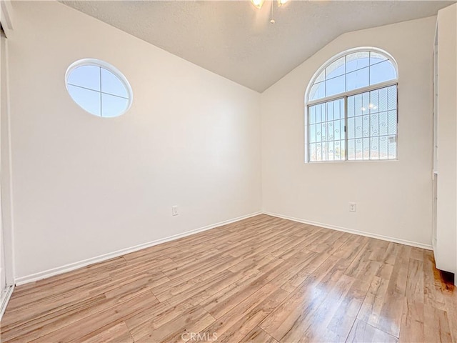 spare room featuring light hardwood / wood-style flooring and lofted ceiling