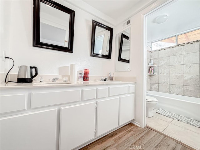 full bathroom featuring tiled shower / bath, vanity, toilet, and hardwood / wood-style floors