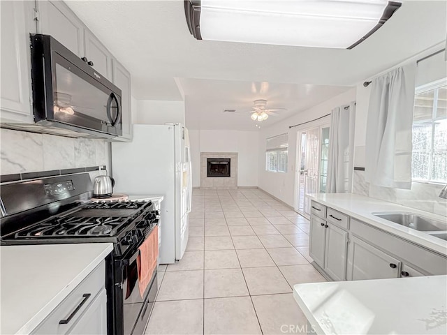 kitchen with white cabinetry, plenty of natural light, a fireplace, and black appliances