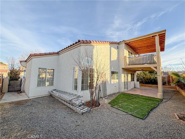 rear view of property featuring a patio and a balcony