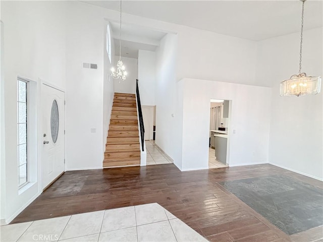 entryway with a healthy amount of sunlight, a chandelier, light tile patterned floors, and a high ceiling