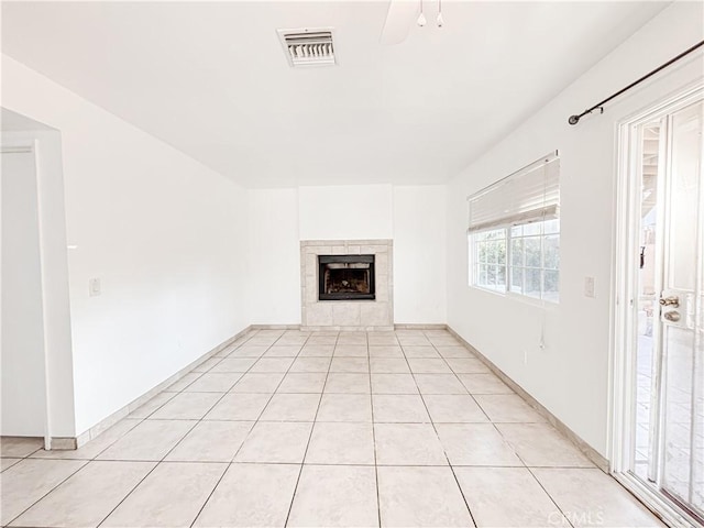 unfurnished living room featuring light tile patterned floors, a tile fireplace, and ceiling fan