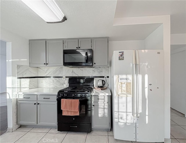 kitchen with gray cabinetry, light tile patterned floors, tasteful backsplash, and black appliances