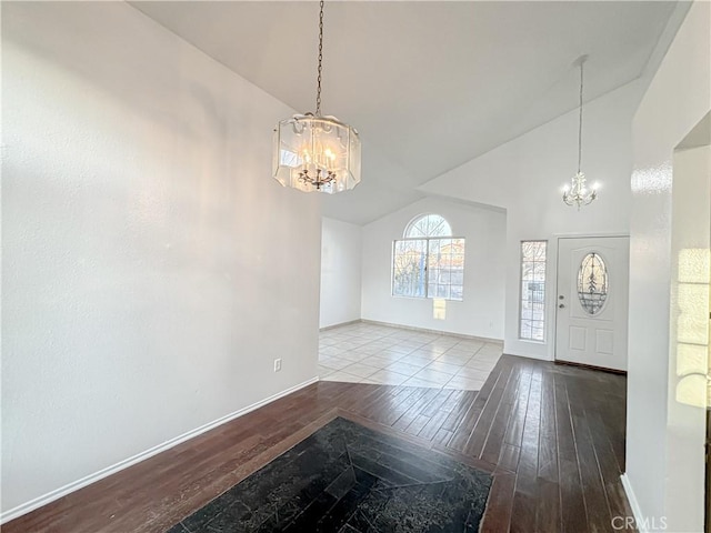 foyer featuring vaulted ceiling, wood-type flooring, and an inviting chandelier