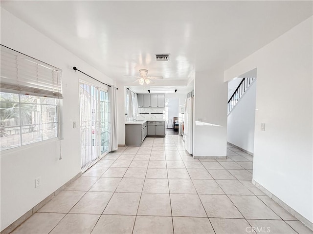 unfurnished living room featuring light tile patterned floors, sink, and ceiling fan