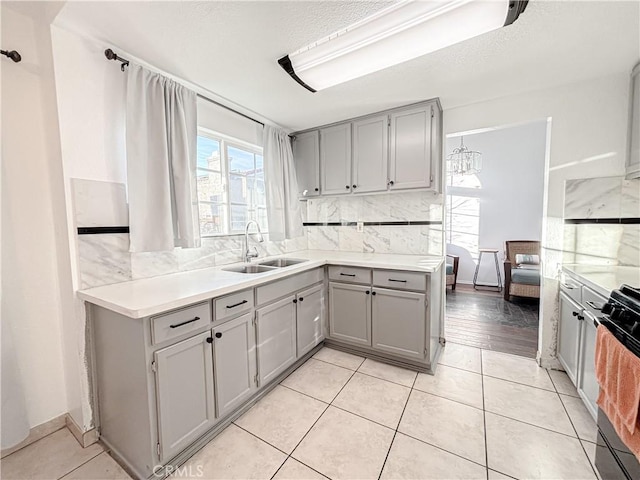 kitchen featuring sink, gray cabinetry, backsplash, and light tile patterned floors