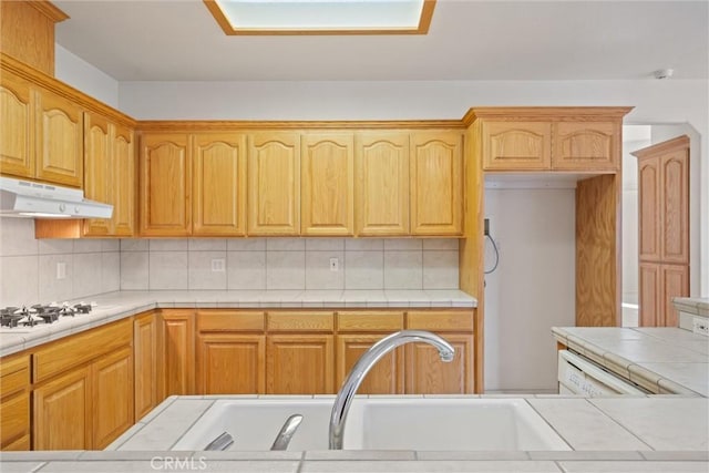 kitchen with white gas cooktop, tile counters, backsplash, and sink