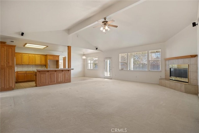 unfurnished living room featuring ceiling fan, beam ceiling, plenty of natural light, and a tile fireplace