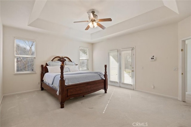 bedroom featuring a raised ceiling, light colored carpet, ceiling fan, and access to outside