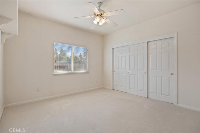 unfurnished bedroom with ceiling fan, light colored carpet, and a closet