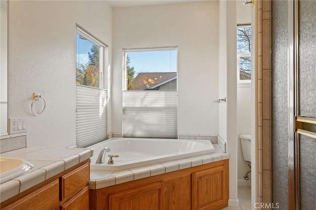 bathroom featuring toilet, a bath, and vanity