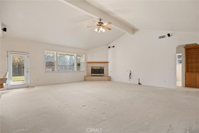 unfurnished living room with light carpet, ceiling fan, a tiled fireplace, high vaulted ceiling, and beamed ceiling