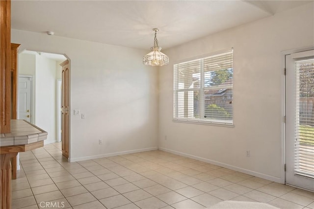 tiled empty room featuring a notable chandelier