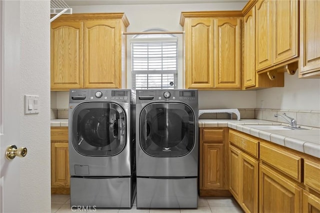 washroom featuring light tile patterned floors, washer and clothes dryer, sink, and cabinets