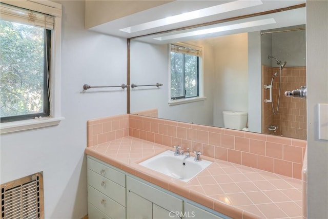 bathroom with toilet, a shower, vanity, and heating unit