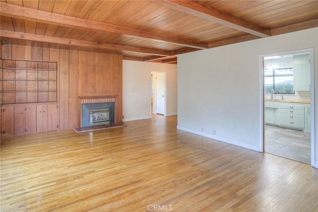 unfurnished living room with light hardwood / wood-style floors, wooden ceiling, beam ceiling, and a fireplace