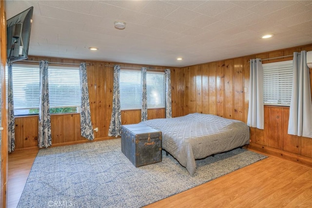 bedroom with multiple windows, hardwood / wood-style floors, and wooden walls