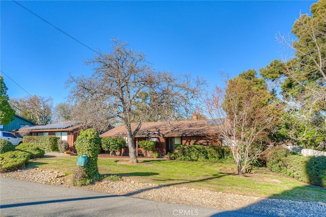 ranch-style home with a front lawn and solar panels