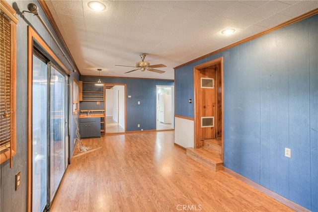 unfurnished living room featuring ceiling fan, ornamental molding, and light hardwood / wood-style floors