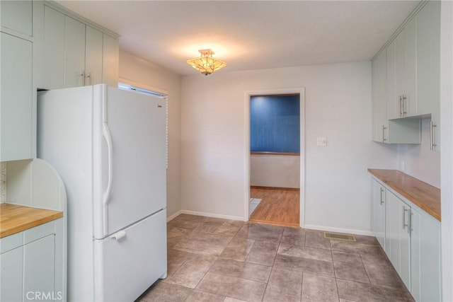 kitchen with butcher block counters and white refrigerator