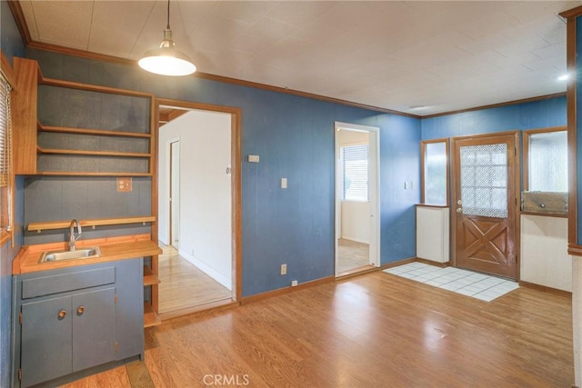 kitchen with wood-type flooring, sink, hanging light fixtures, gray cabinets, and ornamental molding