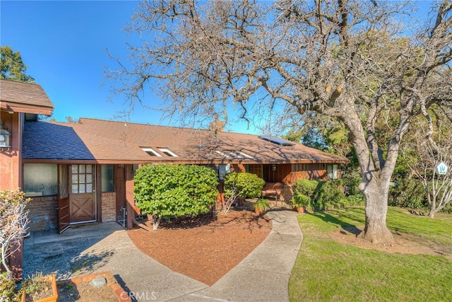 ranch-style home featuring stone siding, roof with shingles, and a front yard