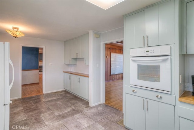 kitchen featuring light wood-type flooring, white appliances, light countertops, and baseboards