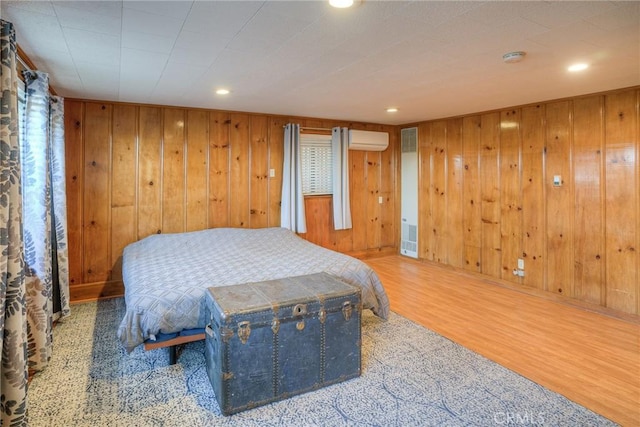 bedroom featuring wooden walls, a wall mounted air conditioner, wood finished floors, and recessed lighting