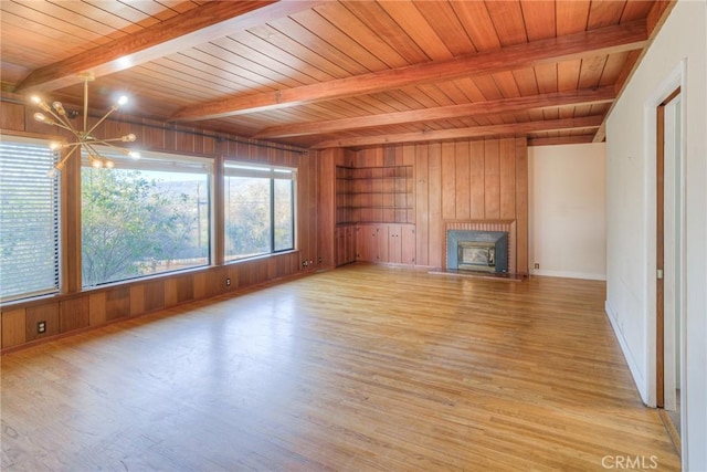 unfurnished living room with plenty of natural light, beamed ceiling, an inviting chandelier, and wooden ceiling