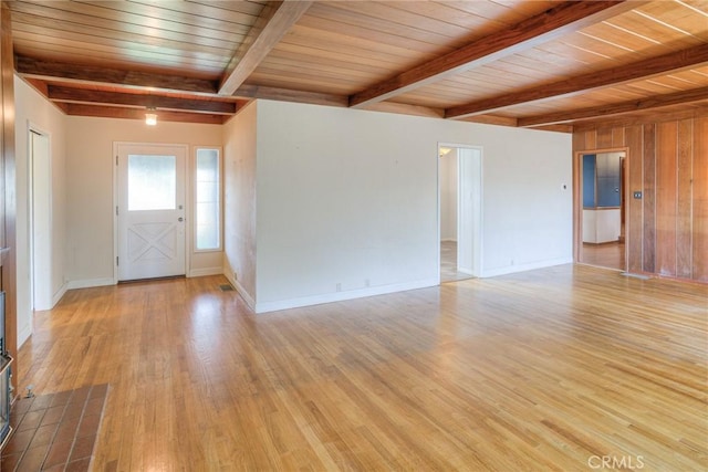 unfurnished living room with beam ceiling, wood ceiling, and light wood-type flooring