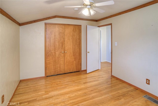 unfurnished bedroom featuring ceiling fan, a closet, ornamental molding, and light hardwood / wood-style flooring