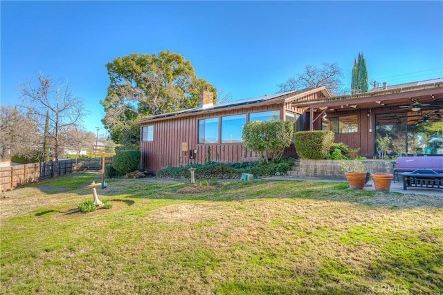 view of front of house featuring board and batten siding, a front yard, a fenced backyard, and a chimney