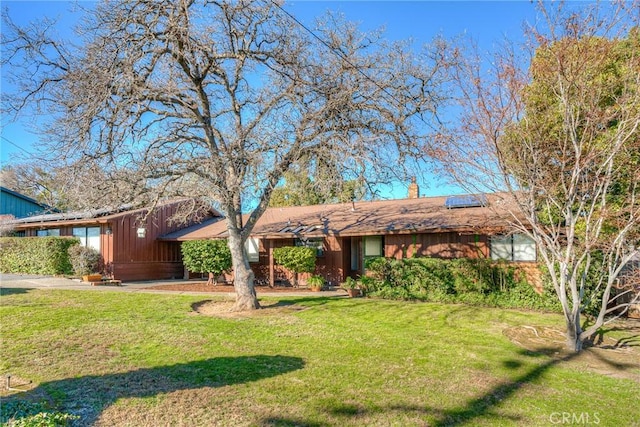 ranch-style home with a front lawn and solar panels