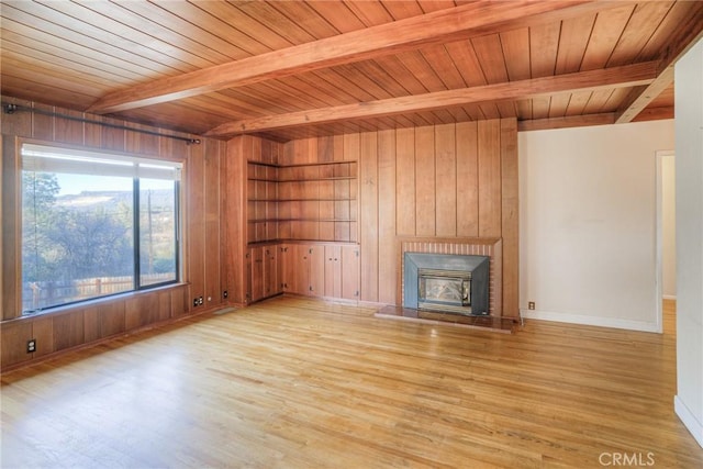 unfurnished living room featuring beamed ceiling and wooden walls