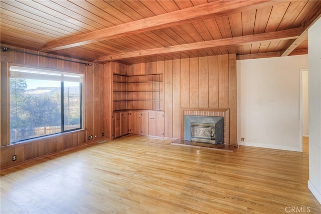 unfurnished living room featuring light wood finished floors, wooden walls, and beamed ceiling