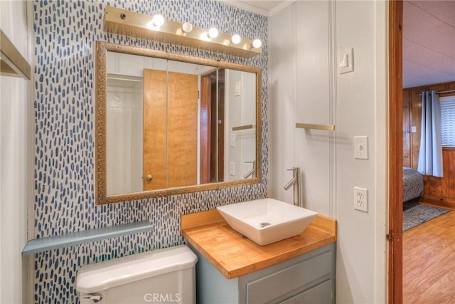 bathroom featuring toilet, ornamental molding, hardwood / wood-style floors, and vanity