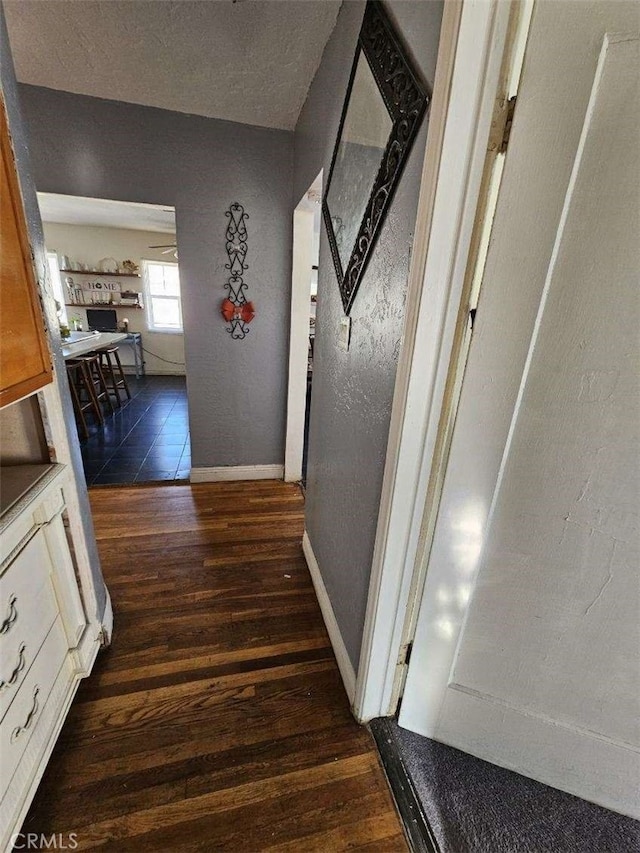 corridor with dark wood-style floors and baseboards