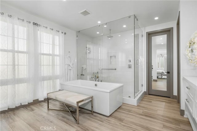 bathroom with independent shower and bath and hardwood / wood-style floors