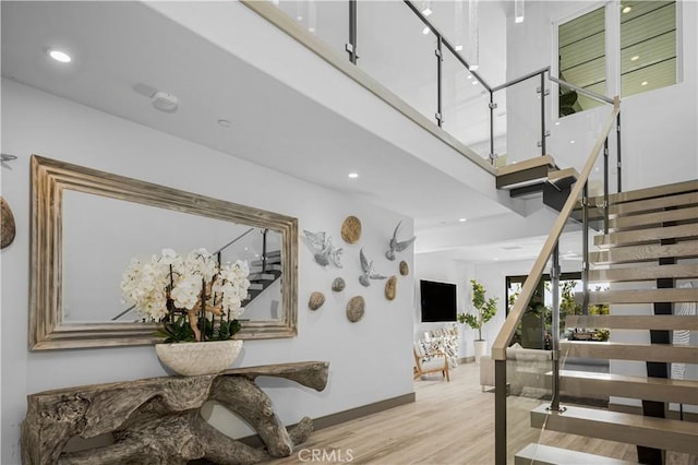 staircase featuring a towering ceiling and wood-type flooring