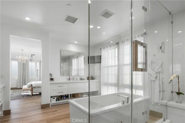 bathroom featuring hardwood / wood-style flooring, vanity, separate shower and tub, and a chandelier