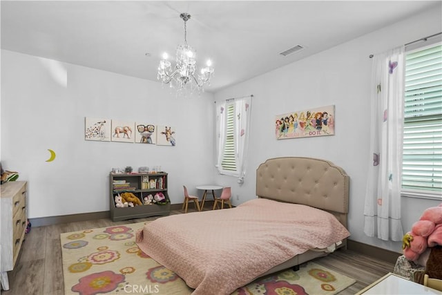 bedroom featuring a notable chandelier, multiple windows, and light wood-type flooring