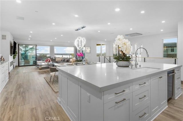 kitchen featuring sink, light wood-type flooring, pendant lighting, a large island, and white cabinets