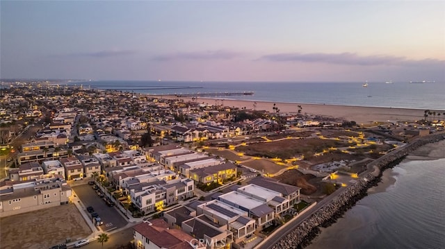 aerial view at dusk with a beach view and a water view