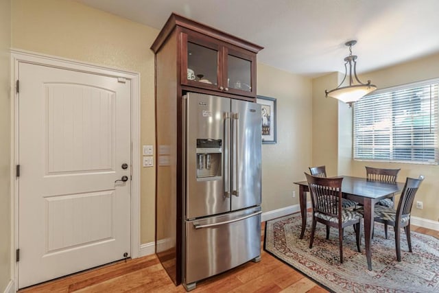 kitchen featuring hanging light fixtures, light wood-type flooring, dark brown cabinets, and high quality fridge