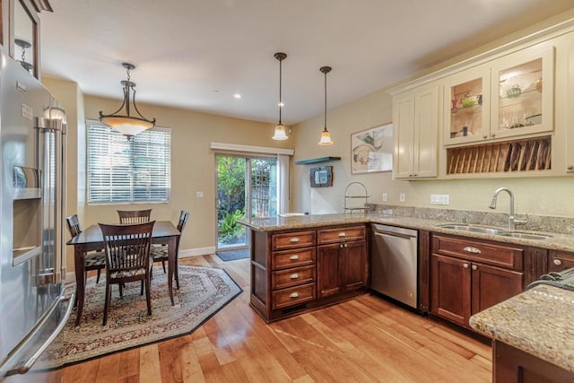 kitchen featuring decorative light fixtures, sink, stainless steel appliances, and light wood-type flooring