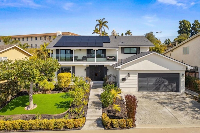 view of front of house with a garage, a front lawn, a balcony, and solar panels