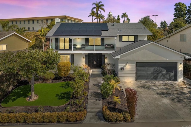 view of front of home with a yard, a garage, and solar panels